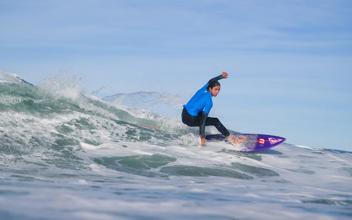 Surfer carving through a wave under clear skies